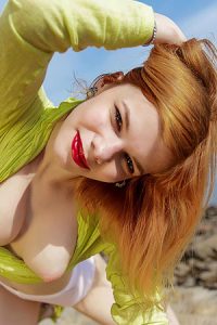 Cute redhead stripping by the sea